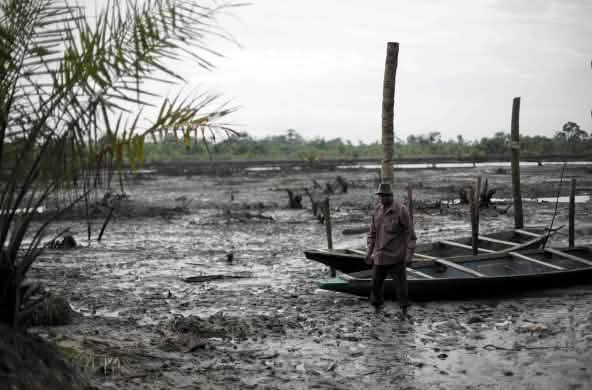 Un homme se tient debout dans le lit d’une rivière polluée par le pétrole dans le delta du Niger