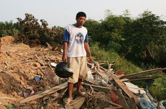Un paysan se tient devant son village en ruines