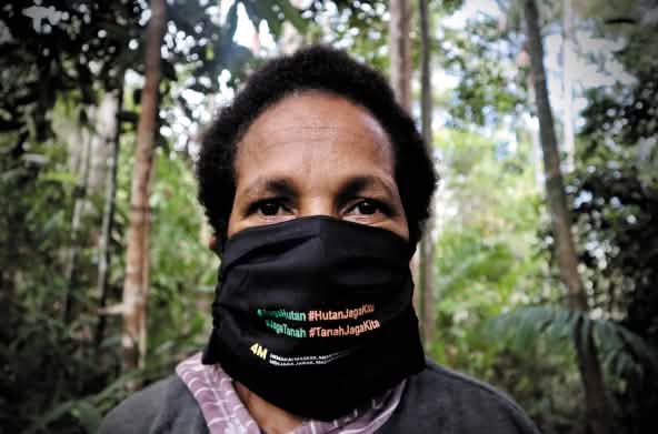 Papoue portant un masque noir sur lequel est écrit : « Protégeons la forêt. La forêt nous protège. »