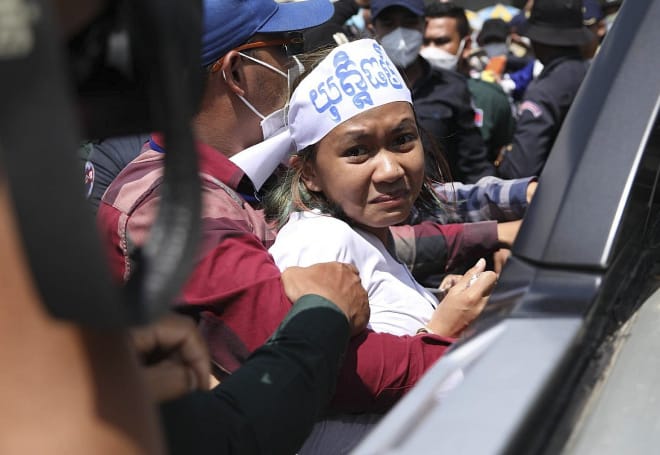 Apeurée, une jeune activiste cambodgienne nous regarde au moment d’entrer dans un véhicule de police