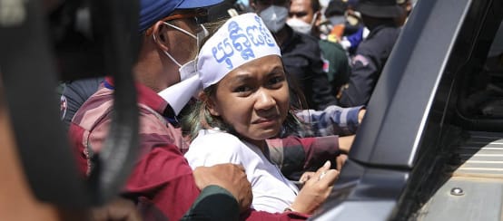 Apeurée, une jeune activiste cambodgienne nous regarde au moment d’entrer dans un véhicule de police