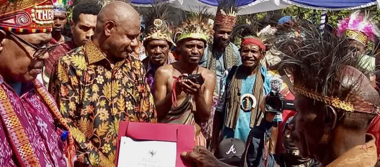Grâce à ce certificat, les indigènes Afsya peuvent faire valoir leurs droits forestiers Un groupe de Papous en vêtements traditionnels tenant un certificat