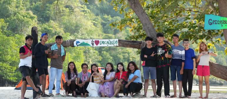 Les membres de Mother Nature Cambodia agissent pacifiquement à la préservation de la nature, ici sur l’île de Koh Kong Un groupe de jeunes assis et debout devant un arbre sur la plage