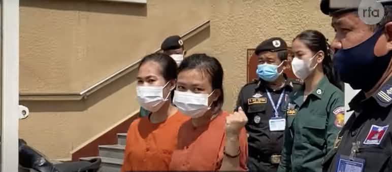 Les écologistes de Mother Nature Cambodia en route vers le tribunal Deux jeunes femmes en tenue de deuil orange, encadrées par des policiers