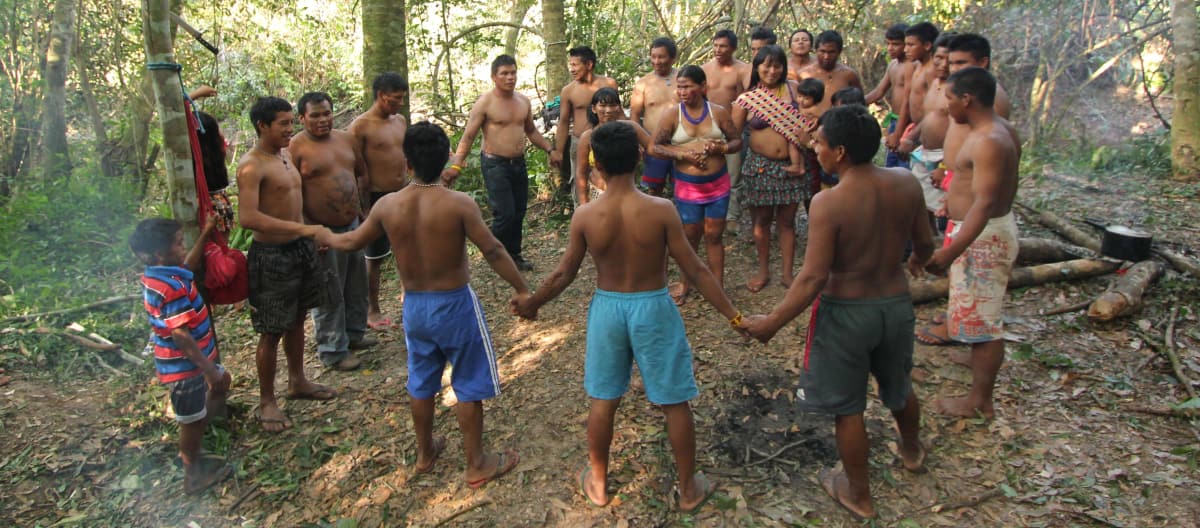 Des indigènes Ka’apor (hommes , femmes et enfants) forment un cercle en se tenant par la main dans la forêt tropicale