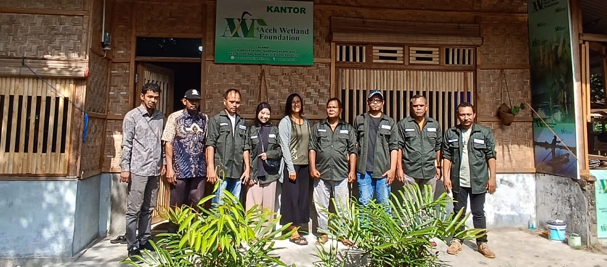 Photo de groupe de la biologiste Rita Glaus de Sauvons la forêt entourée de l’équipe de l’organisation AWF devant son bureau, un édifice en rotin et bambou