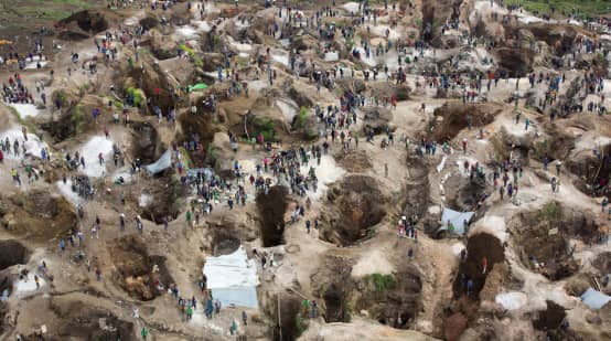 Vue aérienne au-dessus d’une mine, avec trous profonds, en partie remplis d’eau, entre lesquels se trouvent de nombreuses personnes