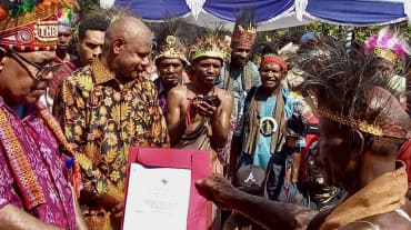 Un groupe de Papous en vêtements traditionnels tenant un certificat