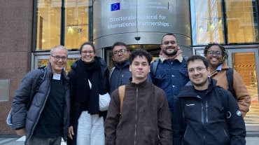 Photo de groupe de 7 personnes devant l’entrée du bâtiment de la Direction générale des partenariats internationaux à Bruxelles