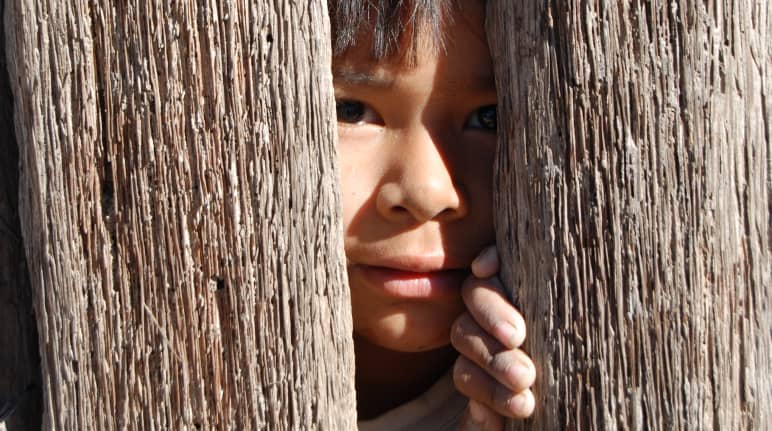 Un enfant regarde entre deux planches de bois