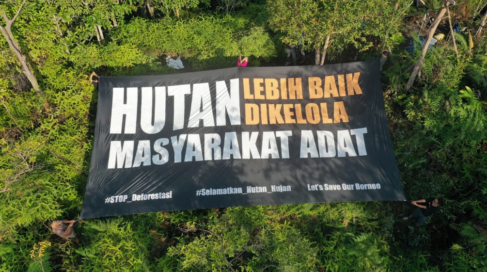 Bannière géante avec texte en indonésien signifiant « Les autochtones sont les meilleurs gardiens de la forêt »