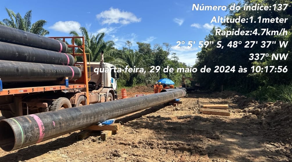 Un camion semi-remorque décharge des tronçons de conduite de pipeline dans la zone déboisée d’un chantier en Amazonie