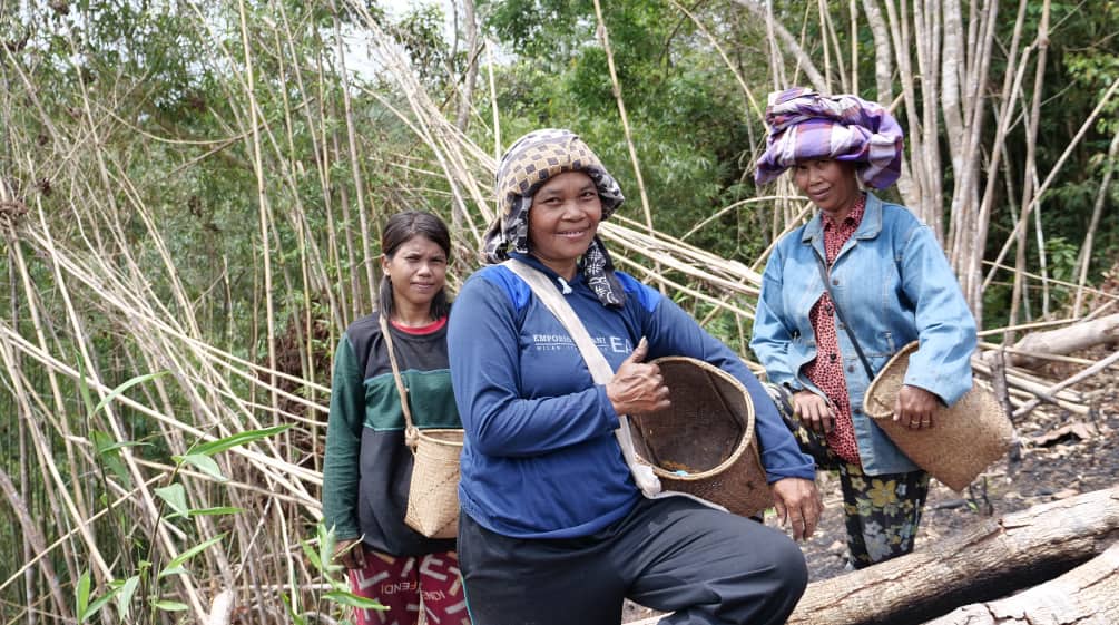 Trois femmes du peuple Dayak avec des paniers pour la cueillette sourient à la caméra