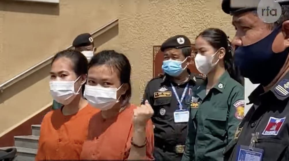 Deux jeunes femmes en tenue de deuil orange, encadrées par des policiers