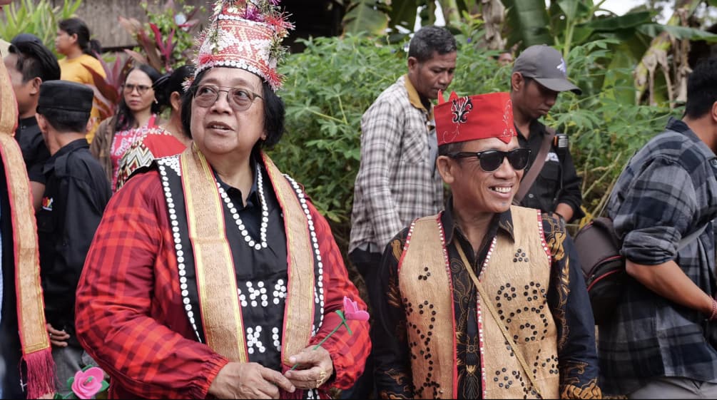 Femme vêtue d’une veste rouge et un homme en costume traditionnel dayak